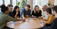 Quatre petits groupes en discussion simultanée dans une salle d'atelier, sans animateur face au groupe
