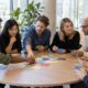 Quatre petits groupes en discussion simultanée dans une salle d'atelier, sans animateur face au groupe
